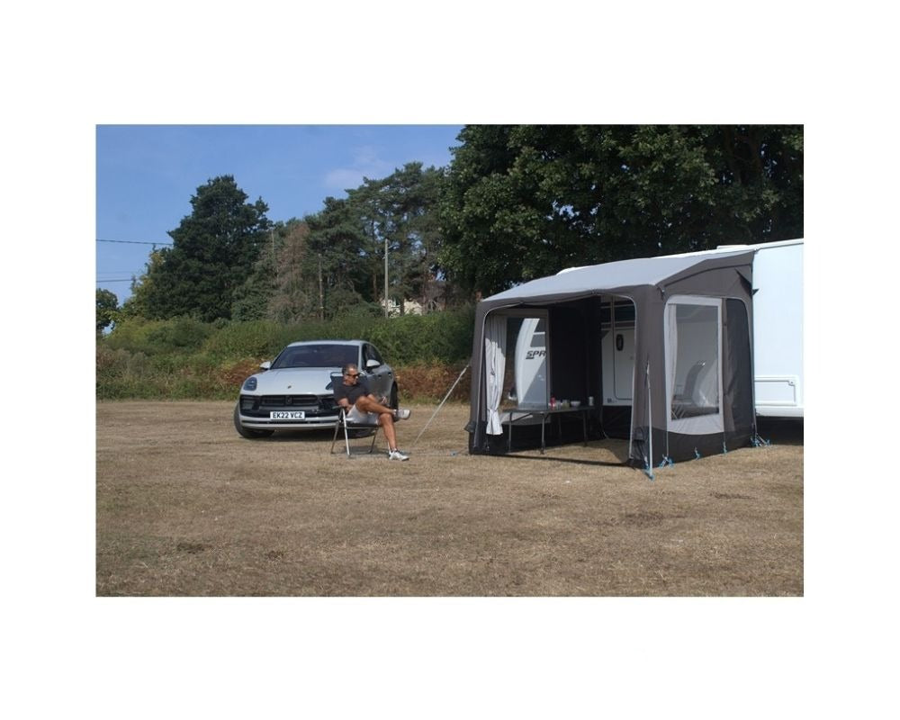Telta Pure 260 vist på campingvogn, med person sittende i en campingstol foran en sølvfarget Porche utenfor teltet