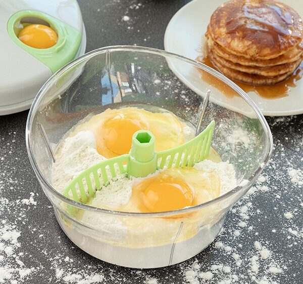 kjøkkenmaskin brukes til å lage pannekakerøre med egg og mel i beholder og ferdige pannekaker på asjett
