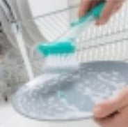 oppvaskbørste med håndtak og såpedispenser skylles over vask